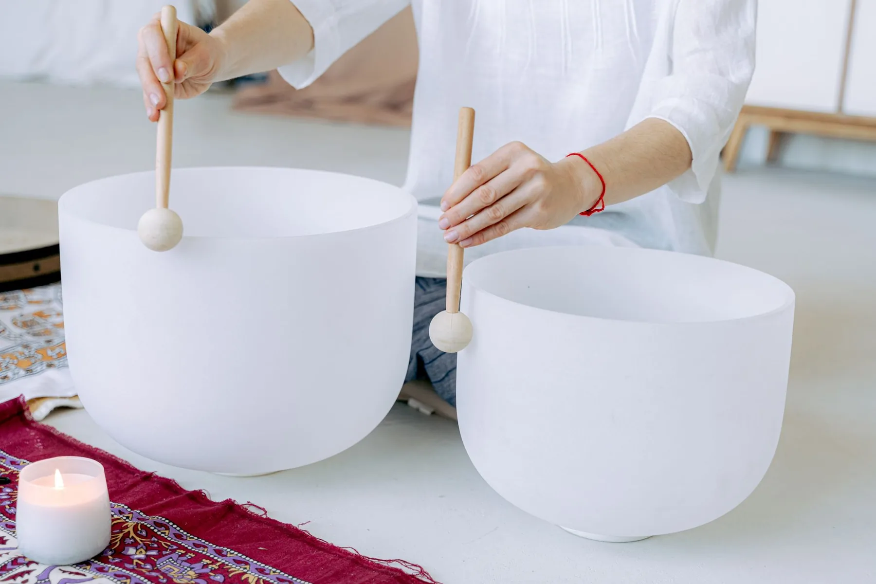 hands playing white Tibetan singing bowls